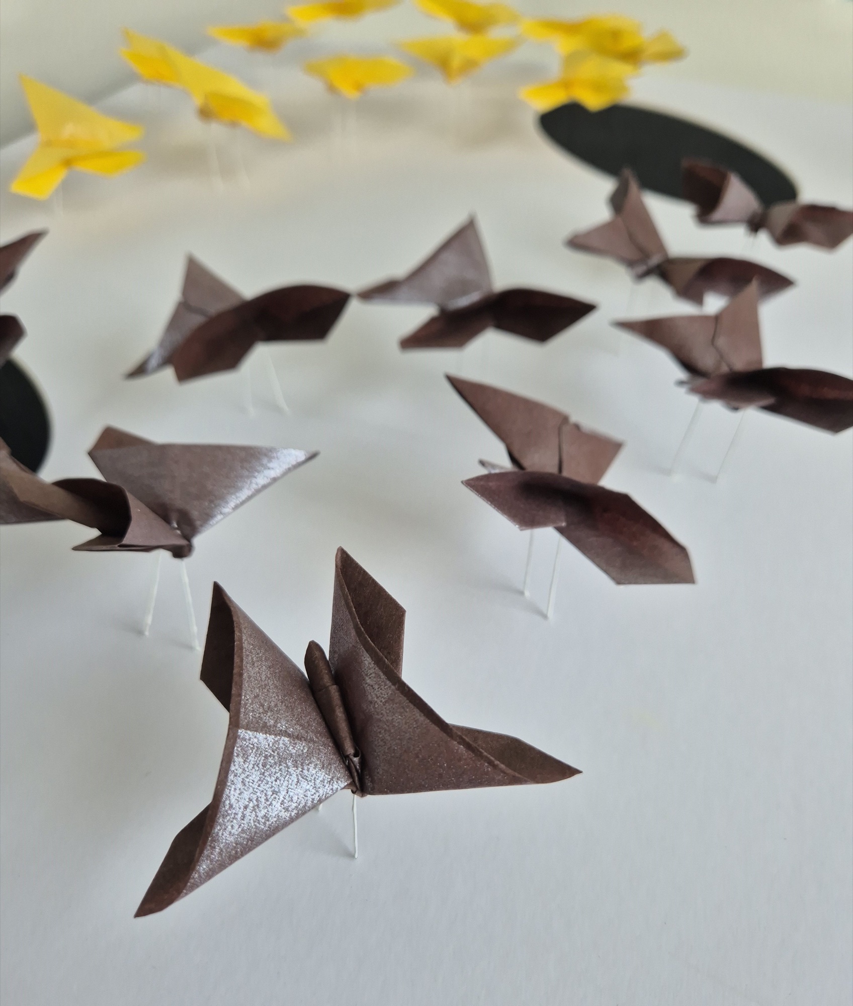 Close view of brown origami butterflies above painted canvas.