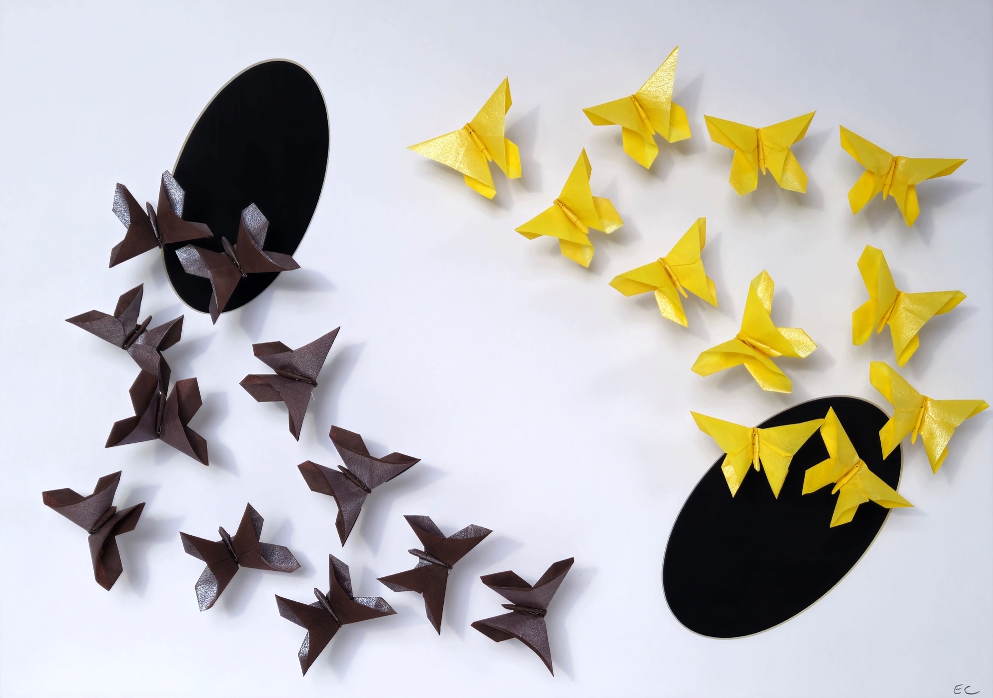 Brown and yellow origami butterflies flying between two black circles.