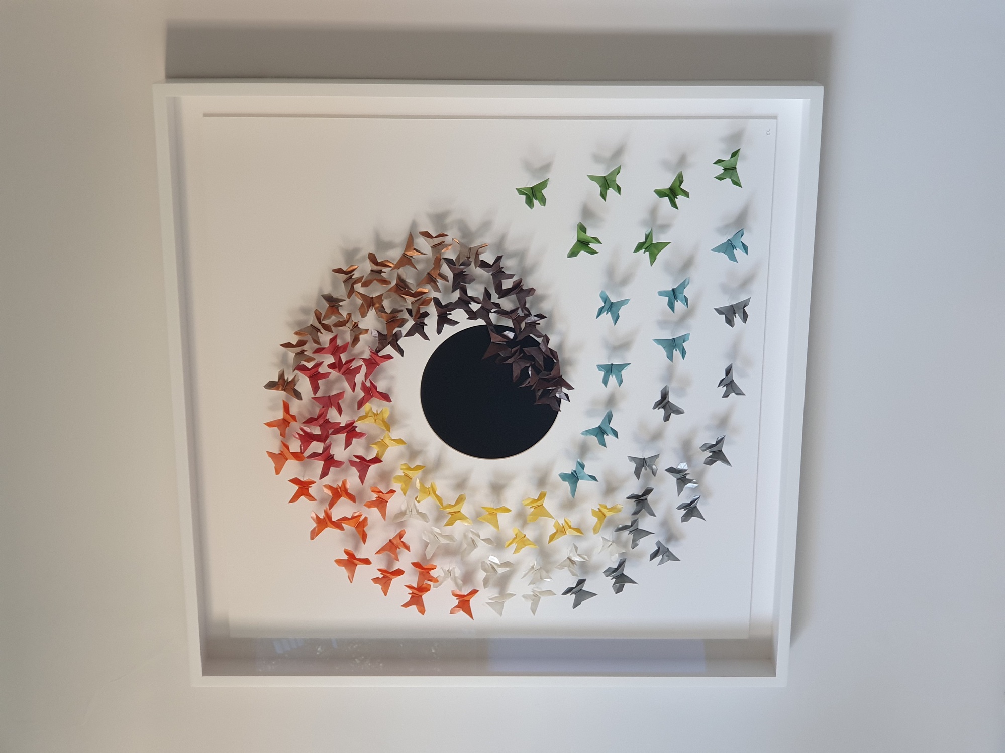 Multi-coloured origami butterflies swirling around a black circle.